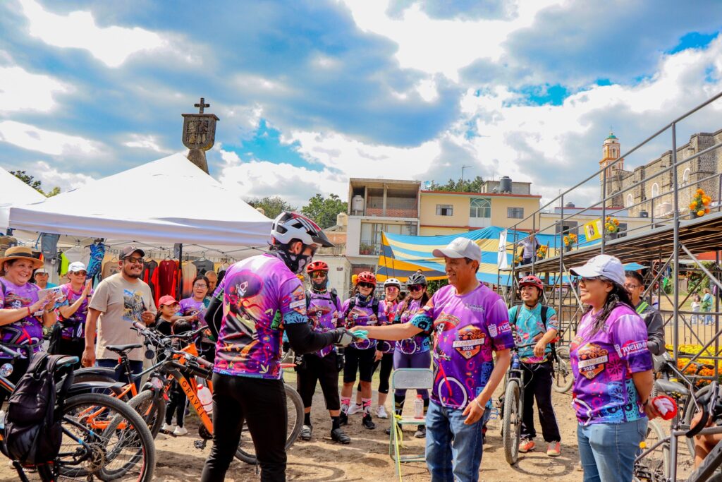 Turismo rural y comunitario en Tochimilco: residente local apoya a un ciclista de MTB durante el evento organizado por Lambdascore, demostrando la calidez de la comunidad.